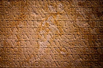 Ancient latin text carved onto a stone tablet, full frame.