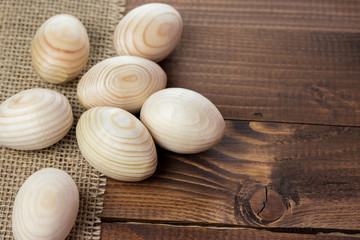 Beautiful wooden Easter eggs lying on the sacking and old brown boards, with free space for your text