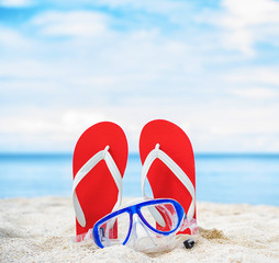 Mask and filp flop on the beach with blue sky and sea background