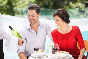 Waiter showing wine bottle to couple 