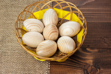 Beautiful wooden Easter eggs are in a wicker nest on old wooden background with free space for your text