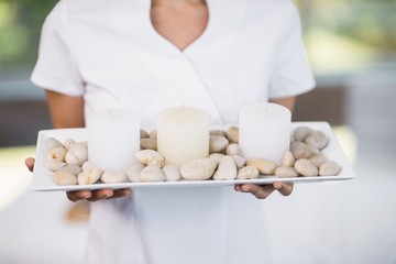Fototapeta na wymiar Masseur holding tray with pebbles and candles