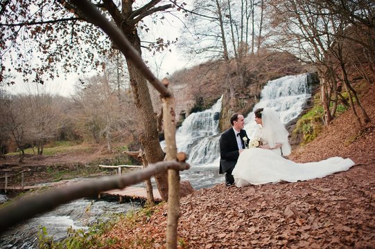 lovely newlyweds background waterfall at cold autumn day