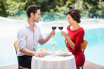 Smiling couple toasting red wine 