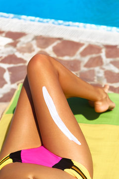 Woman apply cream on her smooth tanned legs.Sun protection lotion