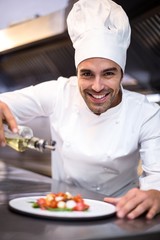 Handsome chef pouring olive oil on meal
