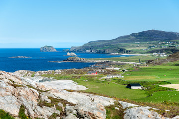 Fototapeta na wymiar Malin Head, Ireland: coastal scenery with red house and hills in the background