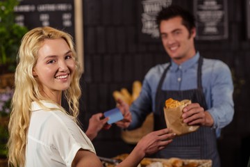 Portrait of a smiling woman paying with credit card