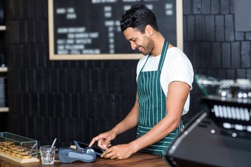 Fototapeta na wymiar Handsome barista using cash register