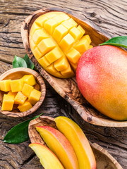Mango fruit and mango cubes on the wooden table. © volff