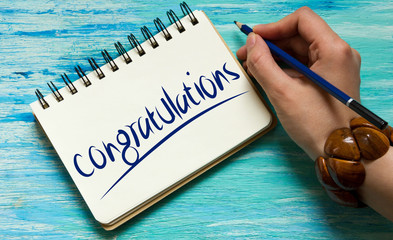 congratulations  inspirational quotes lettering for postcards, business ideas, announcements, write a note with beautiful handwriting of a female hand notebook. wooden background