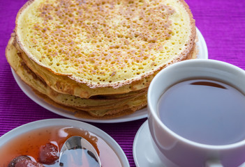 Pancakes with strawberry jam and a cup of tea