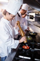 Chef sprinkling pepper on tomatos 