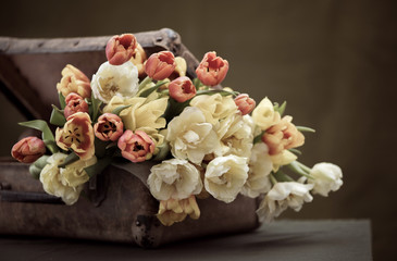 A bunch of beautiful flowers in an old shabby suitcase. On the g