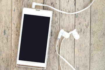 smart phone and earphones on wood background