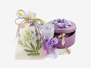 beautiful gorgeous golden earings in violet gemstone box,  aroma candle in glass decorated with artificial flowers and linen sack. on white background.