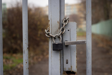 Padlock with iron chain on the old gray fence; locked location