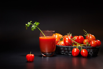 Glass of tomato juice with vegetables on black background
