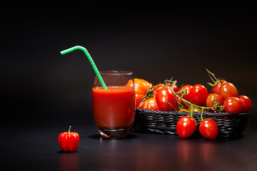 Glass of tomato juice with vegetables on black background