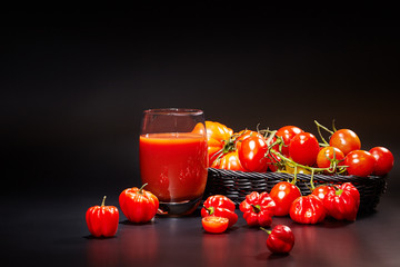 Glass of tomato juice with vegetables on black background
