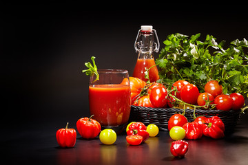 Glass of tomato juice with vegetables on black background