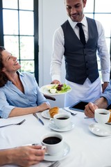 Waiter serving salad to business people