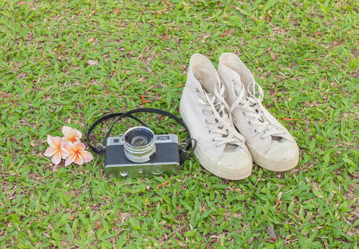 Retro camerar and sneakers on  the grass.Warm tones