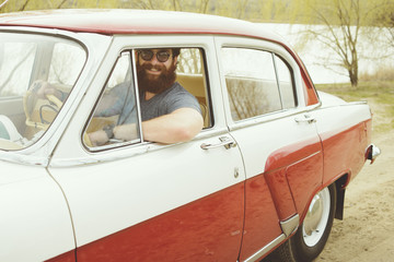 Bearded man behind the wheel of a retro car