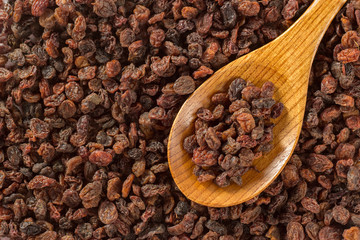 Macro background with a pile of raisins and wooden spoon