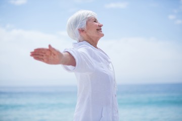 Senior woman smiling while exercising at beach