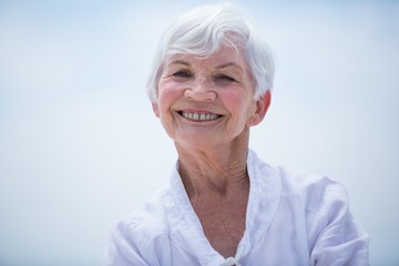 Portrait of smiling senior woman against sky