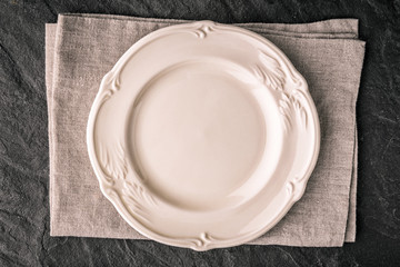 White ceramic plate on the dark stone table top view