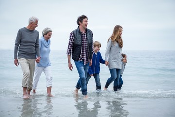 Multi-generation family walking in shallow water at beach