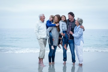 Cheerful family standing at sea shore against sky