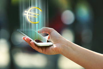 Hand holding a mobile phone with euro sign outdoors, on blurred background