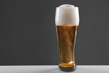 Glass of lager beer on grey background