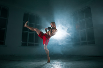 Fototapeta na wymiar The young man kickboxing in blue smoke