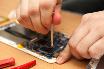 Master repairs the tablet computer. Top view of hands working.