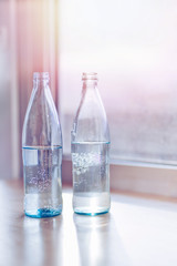 Glass bottles with pure water with sunlight. Film effect.