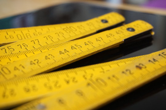 Old yellow folding meter ruler measuring centimeters on the black surface