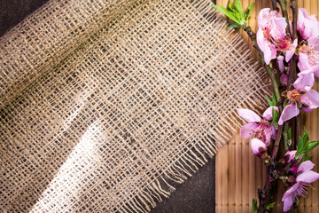 Branch with peach flowers on bamboo and hemp fabric texture 