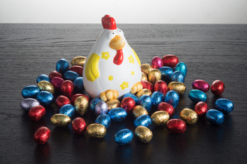 Ovetti  di cioccolato  nella  stagnola colorata con gallina in ceramica su un tavolo