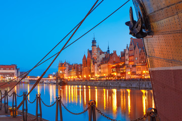 Fototapeta premium Mariacka Gate at the Dlugie Pobrzeze and Motlawa River in old town of Gdansk at night, Poland