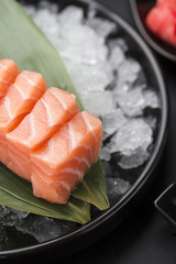 Salmon sashimi on a bamboo list and ice over black background