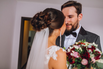 The first meeting of the bride and groom on the wedding day. Emotions newlyweds before the wedding ceremony. Bride and groom look at each other, hugging and kissing. Groom with beard