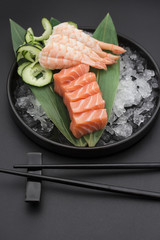 Salmon sashimi on a bamboo list and ice over black background