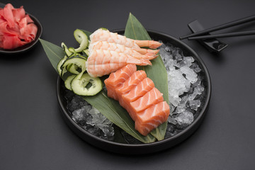 Salmon sashimi on a bamboo list and ice over black background