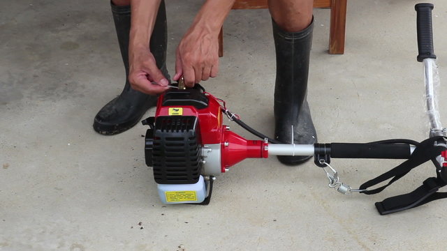 the gardener check the spark plug of lawn trimmer machine