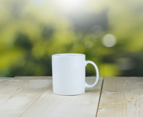 Coffee cup on wood table with green bokeh