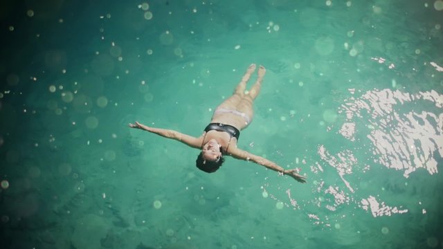 Hispanic woman floats and plays slowly in a natural pool of a sinkhole in Mexico